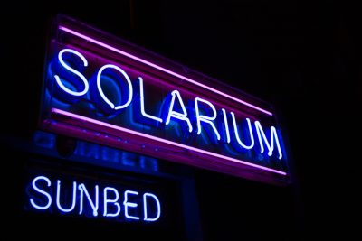 Image of a blue and pink neon sign with the words, "Solarium Sunbed"